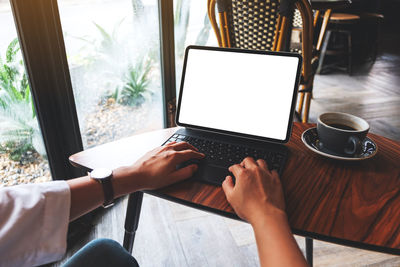 Midsection of woman using laptop on table