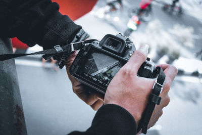 Midsection of man holding camera outdoors