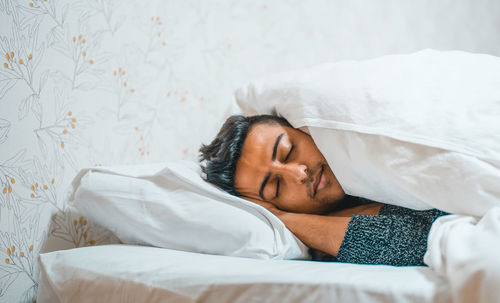 Young man sleeping on bed at home