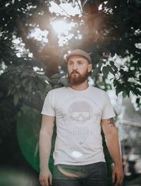 Portrait of young man standing against trees
