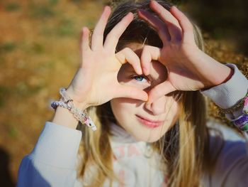 Portrait of girl making heart shape over eyes