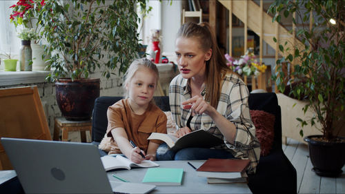 Mother using mobile phone while sitting on table