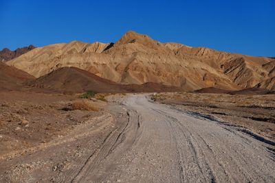 Road in desert against clear blue sky