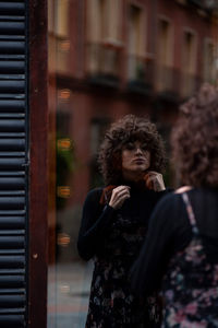 Rear view of woman standing in front of mirror