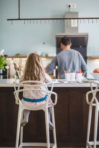 Rear view of father and daughter in kitchen at home