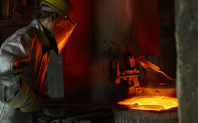 Industry, worker at furnace during melting copper, wearing a fire proximity suit