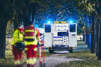 Rear view of paramedic and doctor pushing stretcher outdoors at night