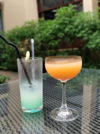 Close-up of drinks on glass table in yard