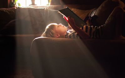 Side view of young boy studying on sofa