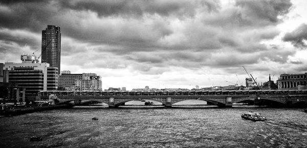 Blackfriars bridge over thames river against cloudy sky in city