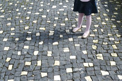 Low section of girl standing on cobblestone street