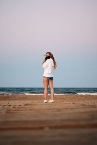 Full length of young woman standing on beach