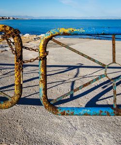 Metallic structure on beach against blue sky