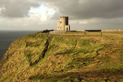 Castle on mountain by sea against sky