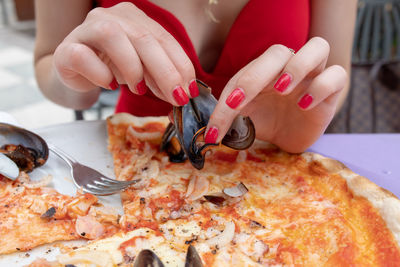 Close-up of hand holding pizza on table