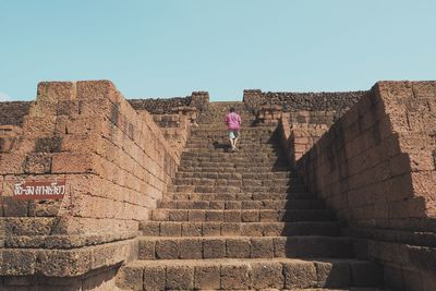 Low angle view of man on staircase against clear sky