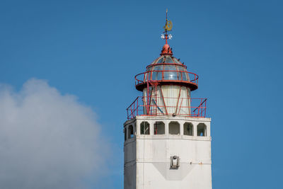 Low angle view of lighthouse by building against sky