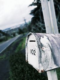 Close-up of mailbox on road against trees