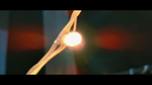 Close-up of illuminated light bulb against sky during sunset