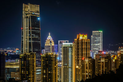 Illuminated buildings in city against sky at night