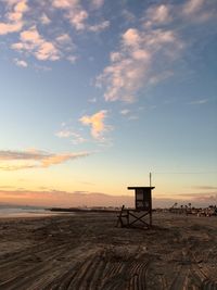 Lifeguard hut on beach against sky during sunset