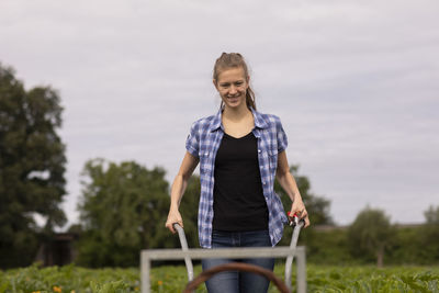 Young woman working as vegetable grower or farmer in the field