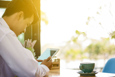 Midsection of man holding coffee cup on table