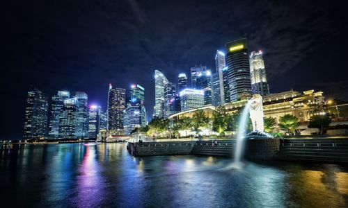 Illuminated buildings by river at night