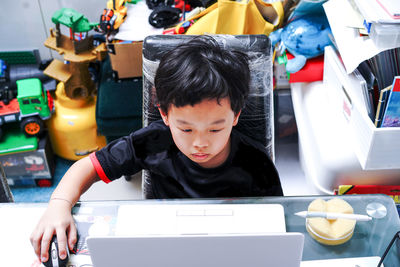 Boy learning over laptop while sitting on table at home