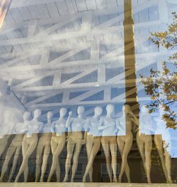 Low angle view of reflection on glass window with mannequins at store