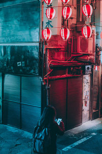 Rear view of woman standing on illuminated street