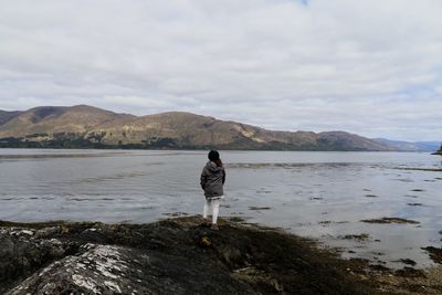 Rear view of man standing on mountain against sky