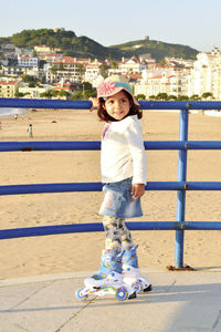 Portrait of smiling girl standing on retaining wall against sea