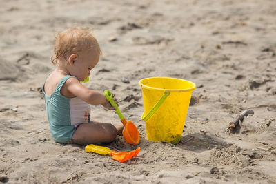 Baby girl playing with toys on sand at beach