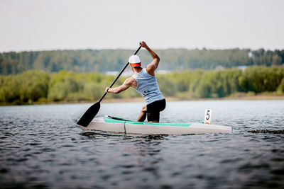 Rear view of man canoeing on lake