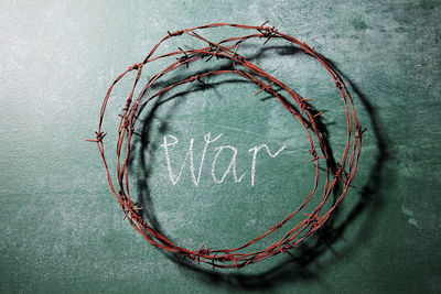 Close-up of rusty barbed wire with text on blackboard