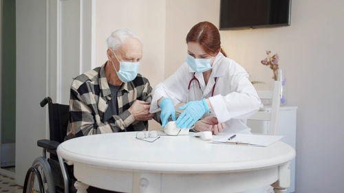 Doctor wearing mask examining patient in clinic