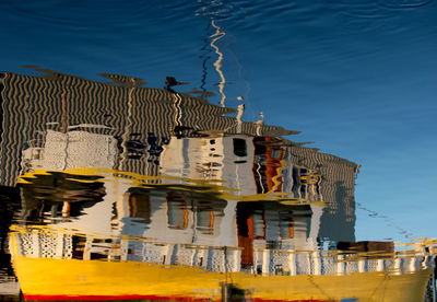 Buildings by sea against blue sky