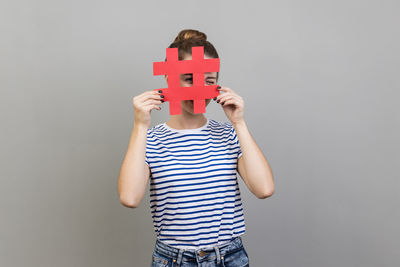 Rear view of woman holding bitcoin against wall