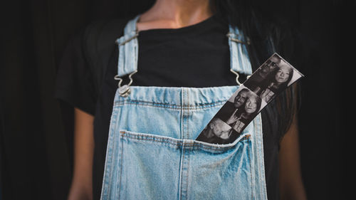 Midsection of woman standing against black background