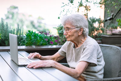 Elderly woman using laptop on terrace