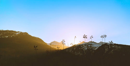 Sunrise over the snowy mountains against clear blue sky