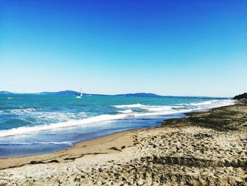 Scenic view of beach against clear blue sky