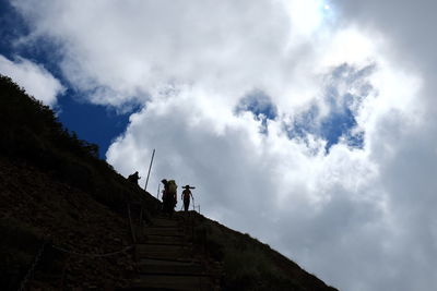 Low angle view of people standing on steps against sky