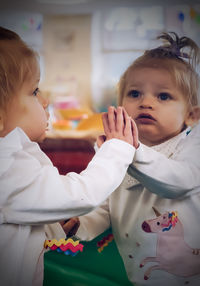 Cute baby girl standing by mirror