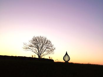 Silhouette bare tree on field against clear sky at sunset