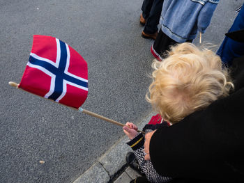 High angle view of woman holding child with flag while standing on road