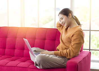 Young woman using phone while sitting on seat