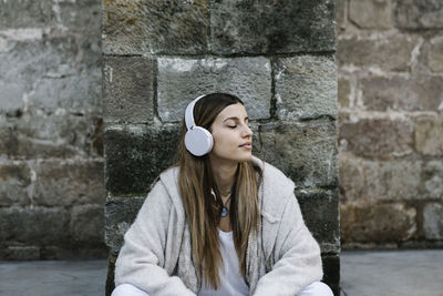 Portrait of a young woman against wall