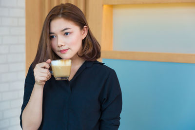 Woman looking away while having coffee at home